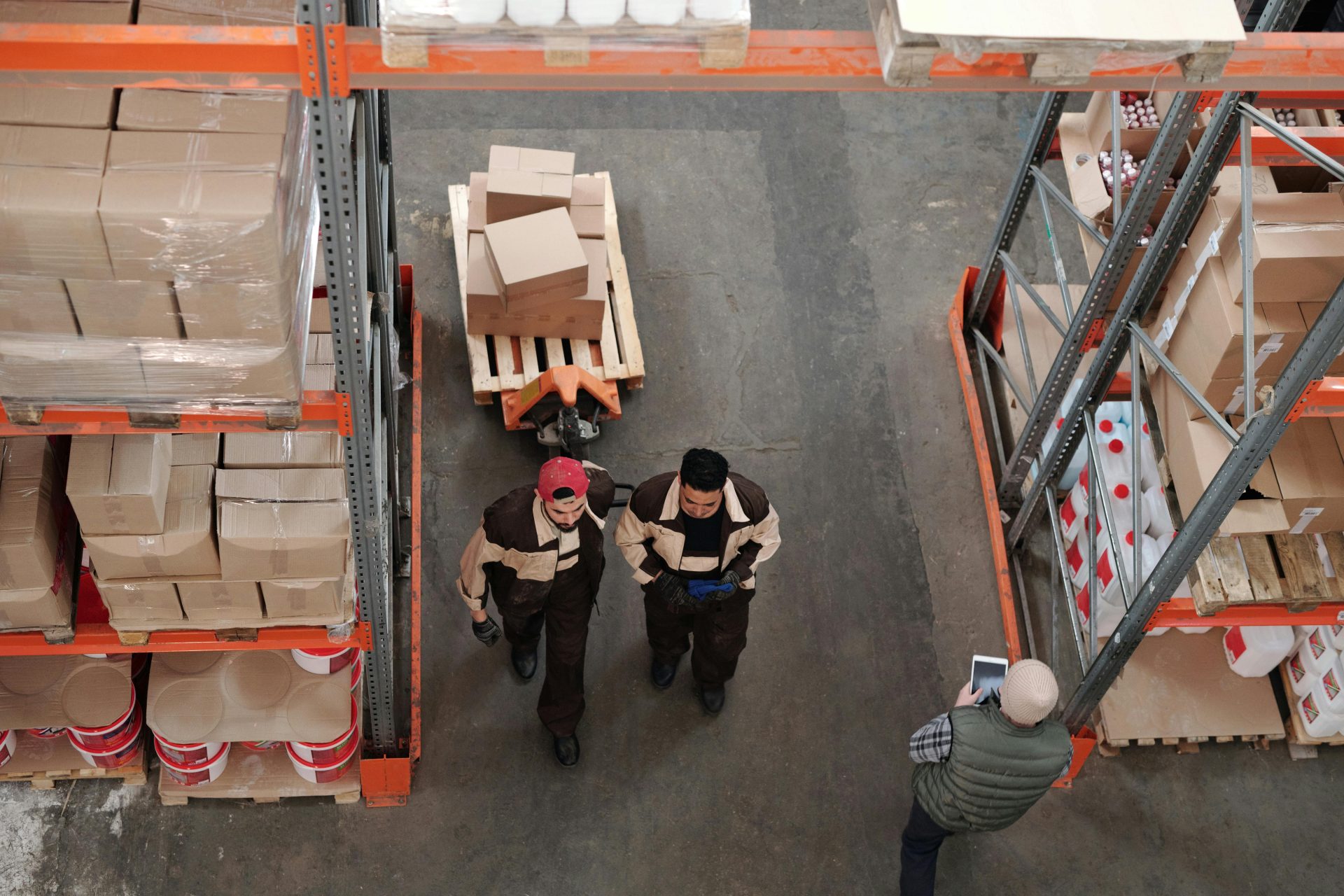Vista de ángulo alto de los trabajadores del almacén organizando y preparando envíos con cajas y paletas.